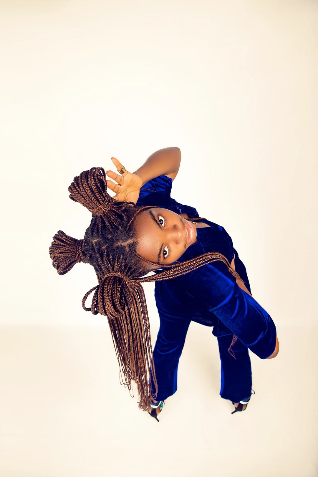 Shot from above, arched back with braids fanned across the cream floor