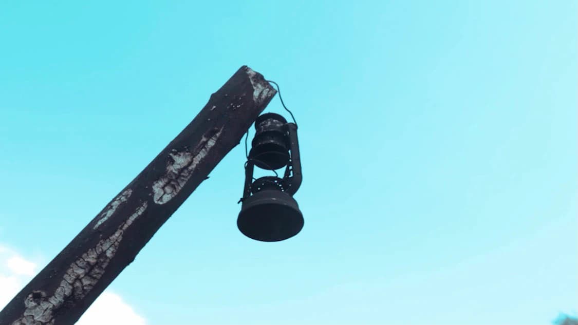 A hurricane lantern hanging from a weathered beam against a pale blue sky