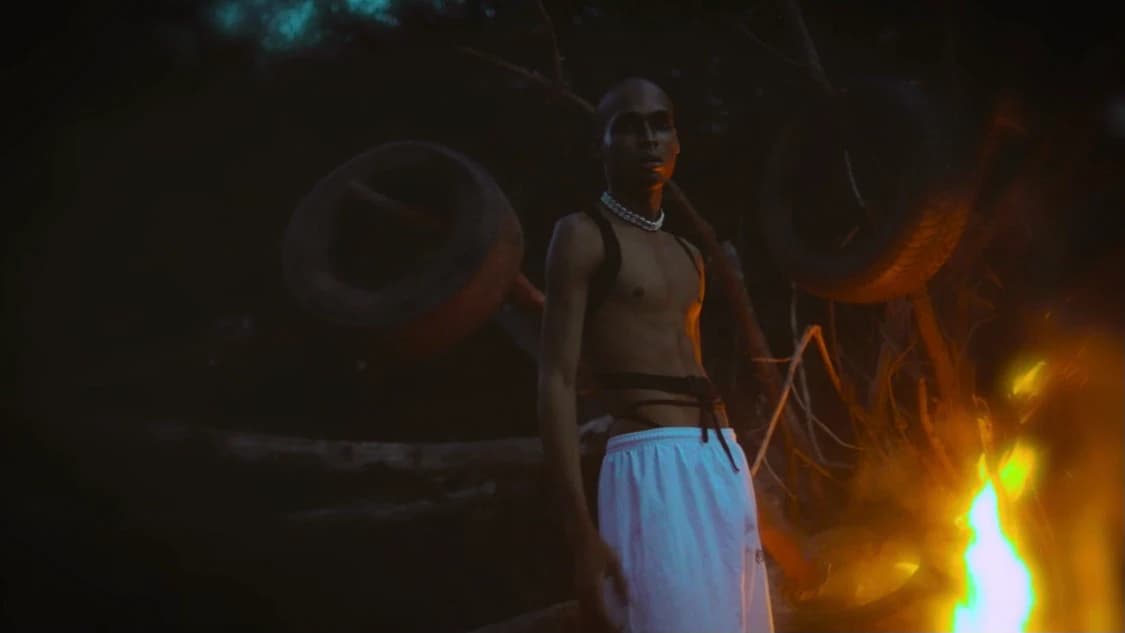 Standing beside an open fire at night, flame filling the lower frame